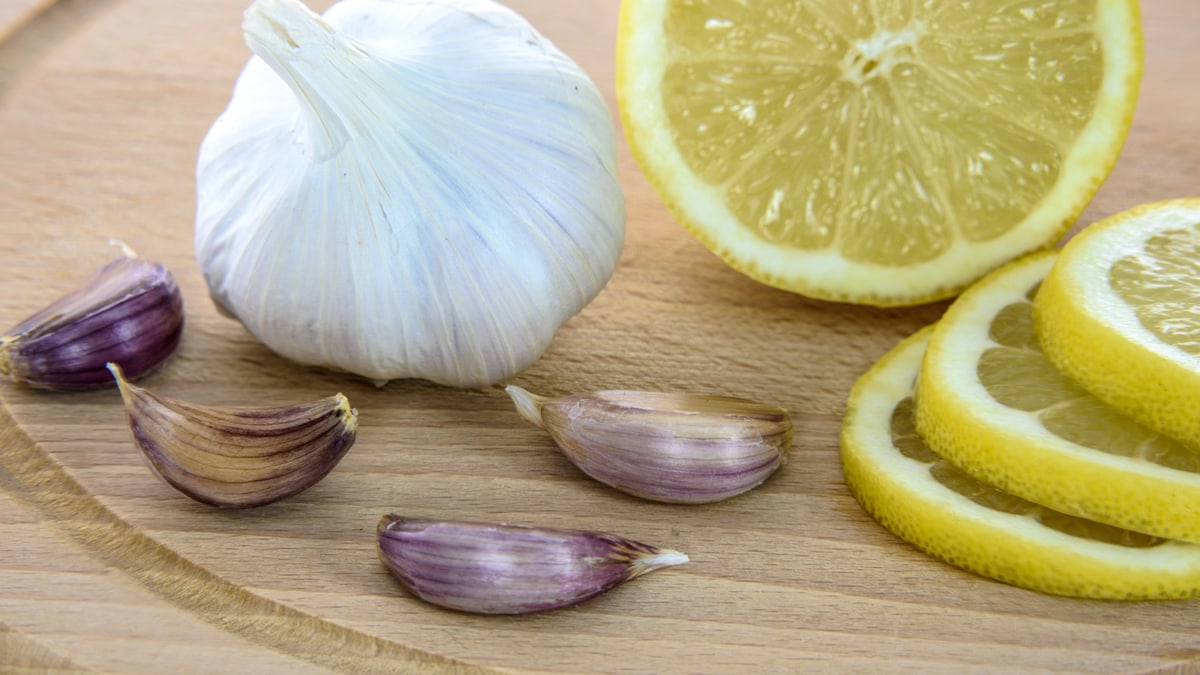 Close-up of fresh garlic and lemon slices on a wooden board, ideal for healthy cooking.